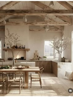 an open kitchen and dining room area with wooden beams on the ceiling, white walls and floor