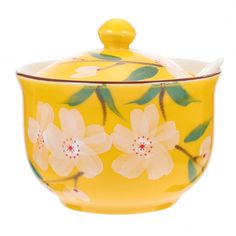 a yellow tea pot with flowers painted on it