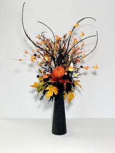 a black vase filled with lots of orange and yellow flowers