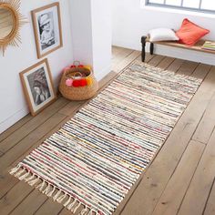 a room with wooden floors and pictures on the wall, including a rug that has been made out of strips of yarn