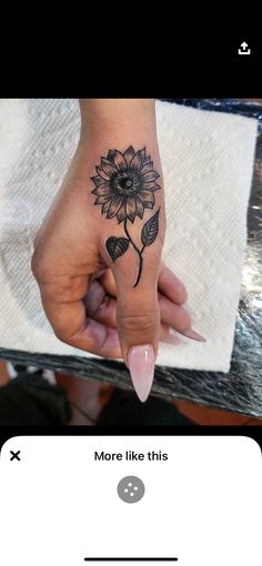 a woman's hand with a sunflower tattoo on her left thumb and the words more like this