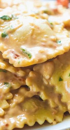 some ravioli with cheese sauce and spinach leaves on top is sitting on a white plate