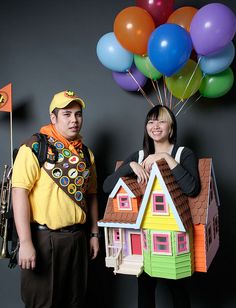 two people standing next to each other with balloons in the air above their heads and houses