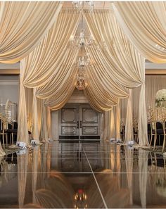 an elegant ballroom with white drapes and chandelier draped over the entrance door