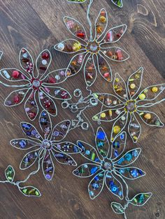 several pieces of art sitting on top of a wooden table next to scissors and beads