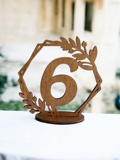 the number six is made out of wood and sits on top of a white table