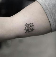 a black and white photo of a maple leaf tattoo on the left inner arm,