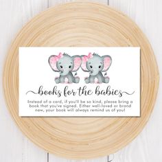 two elephants with pink bows on their ears are sitting next to each other in front of a wooden plate