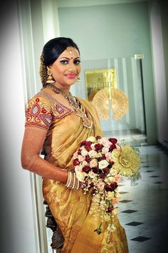 a woman in a yellow sari holding a bouquet of flowers