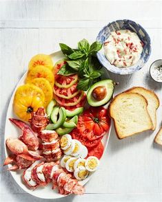 an assortment of food on a plate with bread, tomatoes, cucumbers and avocado