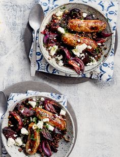 two plates filled with food on top of a blue and white table cloth next to silver spoons