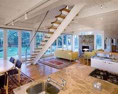 a living room filled with furniture and a fire place under a stair case next to a kitchen