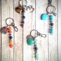 three key chains with different colored beads and charms hanging from them on a wooden surface