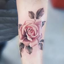 a pink rose tattoo on the left arm