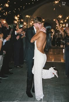 a bride and groom kissing in front of their guests with sparkler wands all around them