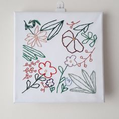 a white wall hanging with flowers and leaves on it