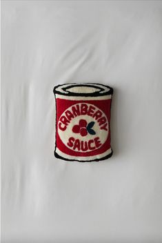 a red and white cup with the words cranberry sauce on it sitting on a white surface