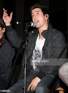 two men sitting in front of microphones and one is singing into the microphone while another man