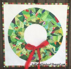 a quilted christmas wreath with red ribbon hanging on the front door frame, decorated with green and red fabric