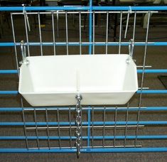 a white sink sitting on top of a metal rack next to blue pipes in a room