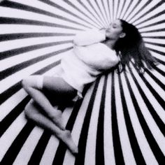 a woman laying on top of a black and white striped umbrella