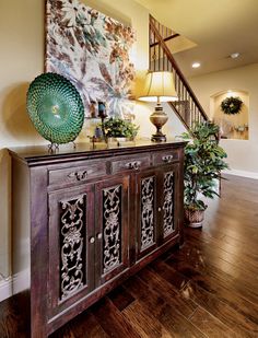 a wooden cabinet sitting in the middle of a living room next to a stair case