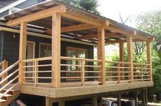 a house with wooden decking and stairs leading to the upper level balcony, which also has an attached porch