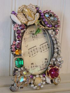 an old photo frame with musical notes and flowers on it, sitting on top of a shelf