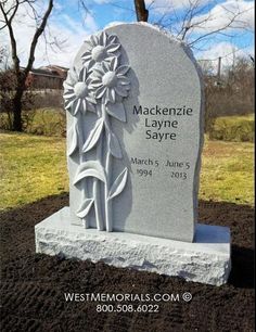 a headstone with flowers on it in the grass