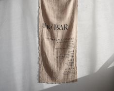 a towel hanging on a wall with the word, the bar written in black ink