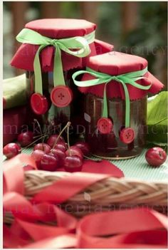 some cherries are in jars with ribbons around them