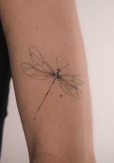 a small dragonfly tattoo on the arm