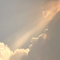 an airplane is flying in the sky with clouds and sunbeams behind it on a sunny day