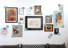 a living room wall with many framed pictures on it's walls and various frames above the couch