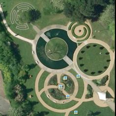 an aerial view of a circular garden in the middle of a park with trees and grass