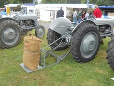 an old tractor is parked on the grass near other antique tractors and people are looking at it