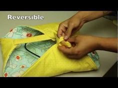 a person is sewing something on a yellow piece of fabric with the words reversible written above it