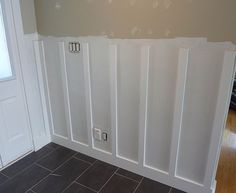 an empty room with white paneling on the wall and wood floors in front of it