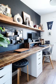 a home office with wooden shelves and white desks, black walls and wood flooring