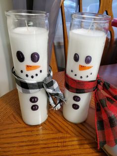 two snowman candles are sitting on a table