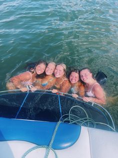 four girls are in the water on a boat with their arms around each other and smiling