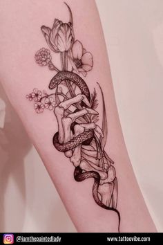 a woman's leg with a tattoo on it and flowers in the corner,