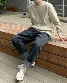 a man wearing a mask sitting on a wooden bench