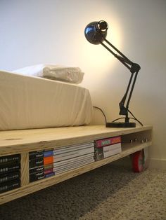 a bed with a lamp on top of it next to a book shelf filled with books