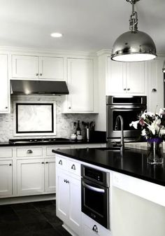 a large kitchen with white cabinets and black counter tops, an island in the middle