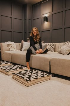 a woman sitting on top of a couch in a living room next to a rug