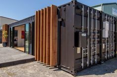 a large metal container sitting on top of a cement floor next to a building with wooden slats