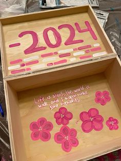 a wooden box with pink flowers painted on it and writing in the bottom right corner