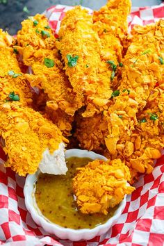 some fried food on a red and white checkered paper with dipping sauce in it