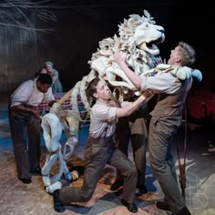 two men are performing on stage with an animal skeleton in the foreground and another man standing next to him